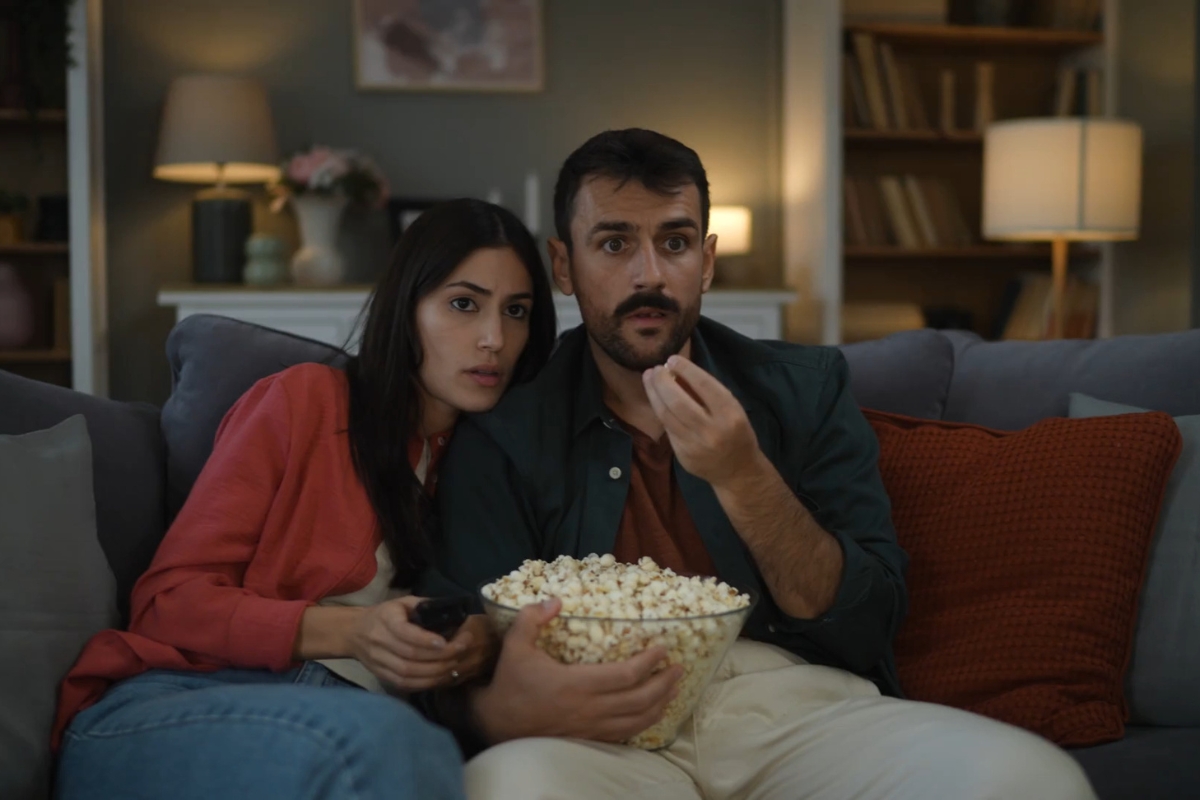 momak i devojka gledaju film i grickaju kokice
